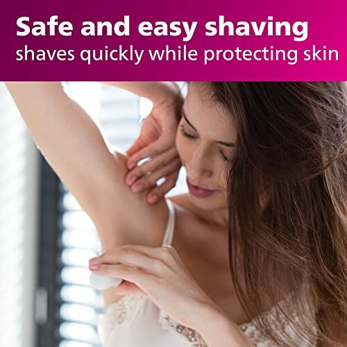 Woman shaving underarm with a smile on her face.